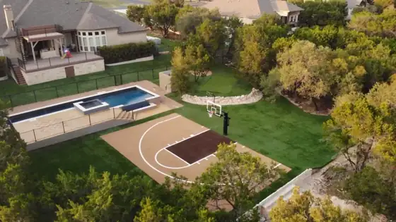 Aerial view of a backyard basketball court next to a pool